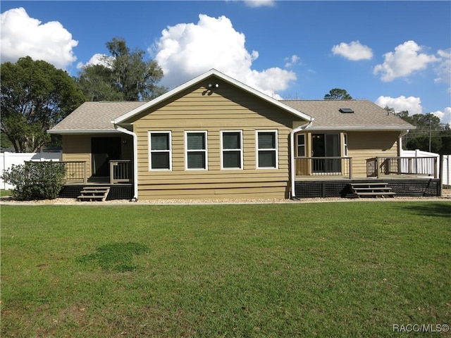 rear view of property with a wooden deck and a lawn