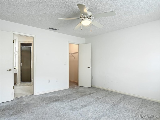 3328 S Whitechappel Pt, Inverness, FL 34452 - unfurnished bedroom with carpet flooring, a walk in closet, a textured ceiling, a closet, and connected bathroom