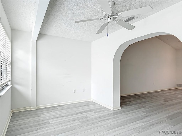 3328 S Whitechappel Pt, Inverness, FL 34452 - empty room featuring arched walkways, ceiling fan, light wood-style floors, and a textured ceiling
