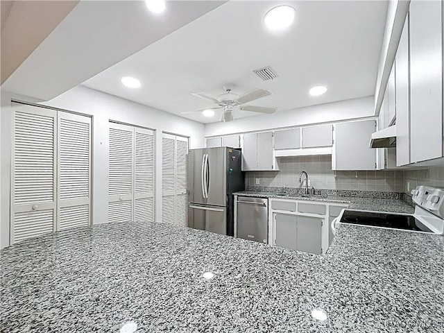 3328 S Whitechappel Pt, Inverness, FL 34452 - kitchen with appliances with stainless steel finishes, under cabinet range hood, dark stone counters, a ceiling fan, and recessed lighting