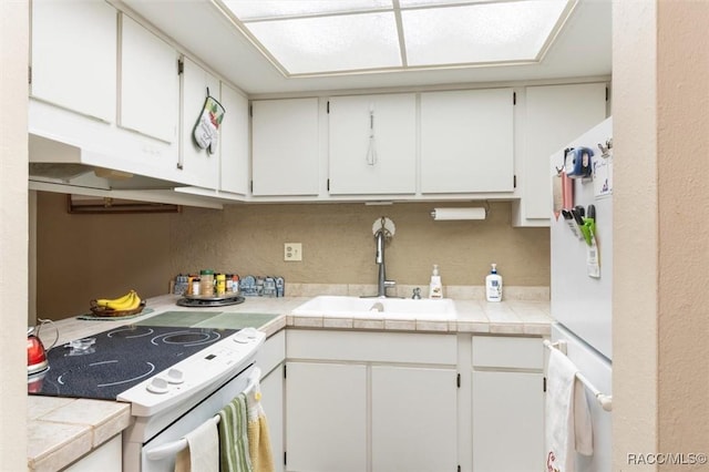 kitchen with tile counters, sink, white cabinets, and white appliances