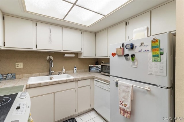 kitchen with white cabinetry, tile counters, sink, white appliances, and light tile patterned floors