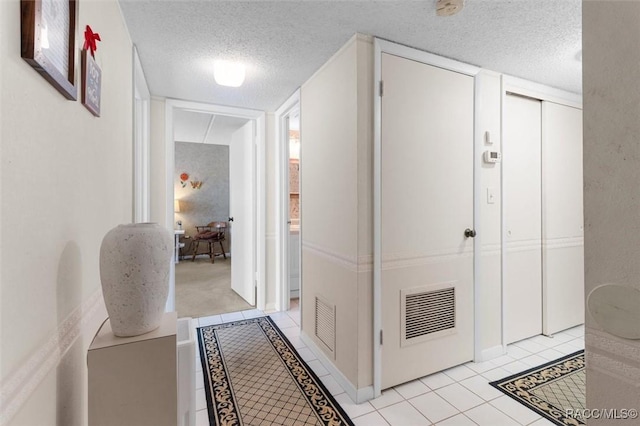 hall featuring light tile patterned floors and a textured ceiling