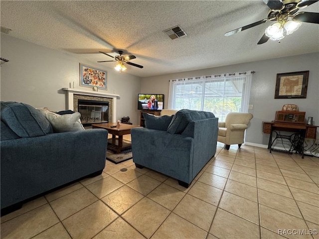 living area featuring a glass covered fireplace, light tile patterned flooring, visible vents, and a textured ceiling