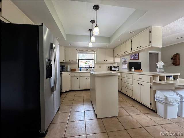 kitchen with a tray ceiling, a peninsula, light countertops, stainless steel refrigerator with ice dispenser, and pendant lighting