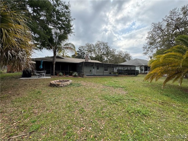 view of yard featuring glass enclosure, a fire pit, and a patio area