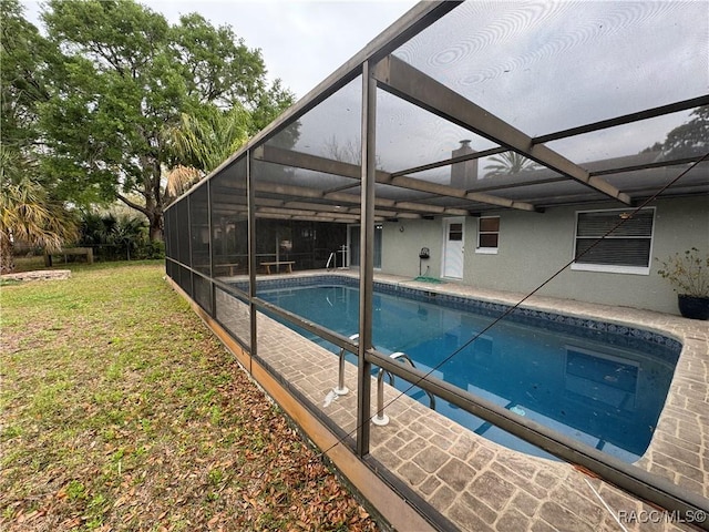 pool with a lanai, a patio area, and a lawn