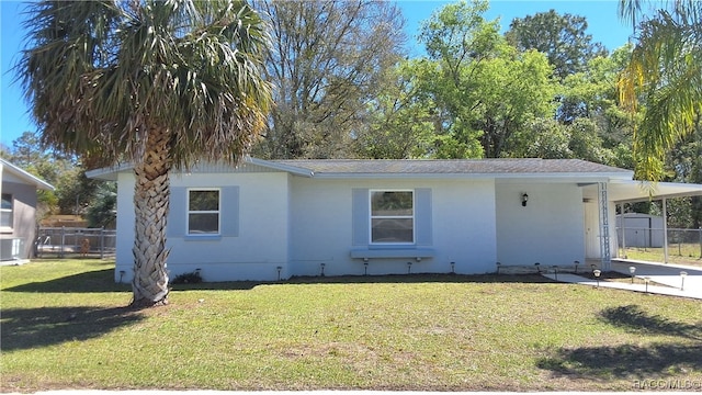 view of front of home featuring an attached carport, driveway, a front lawn, and fence