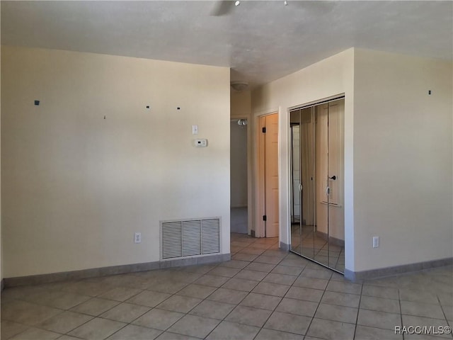 empty room featuring light tile patterned floors, visible vents, and baseboards