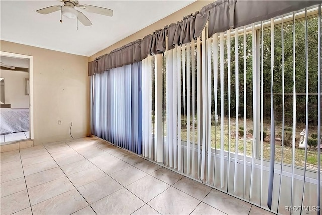 empty room with light tile patterned floors, a wealth of natural light, and ceiling fan