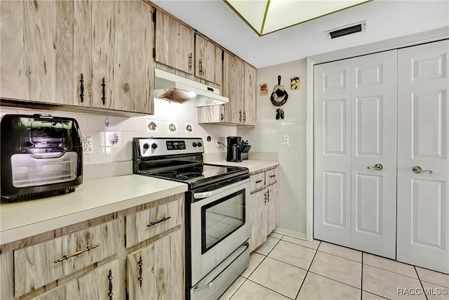 kitchen with light brown cabinetry, tile walls, stainless steel range with electric cooktop, and light tile patterned floors