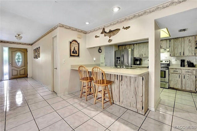 kitchen with light tile patterned floors, sink, appliances with stainless steel finishes, tasteful backsplash, and kitchen peninsula