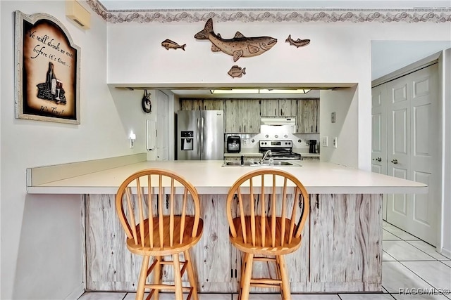 kitchen featuring appliances with stainless steel finishes, light tile patterned floors, a kitchen breakfast bar, and kitchen peninsula