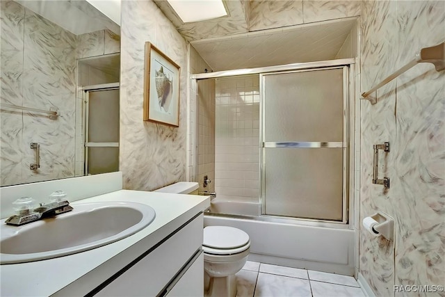 full bathroom featuring tile walls, shower / bath combination with glass door, vanity, toilet, and tile patterned floors