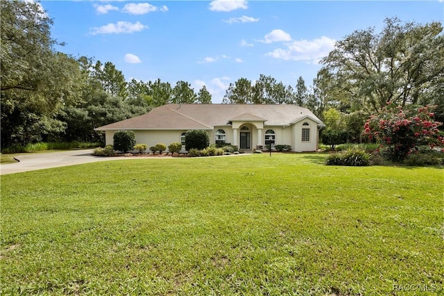 5799 N Oakmont Dr, Beverly Hills, FL 34465 - ranch-style home featuring driveway, a front lawn, stucco siding, and view of scattered trees