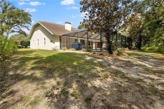 5799 N Oakmont Dr, Beverly Hills, FL 34465 - back of house featuring a chimney, a lawn, glass enclosure, and stucco siding