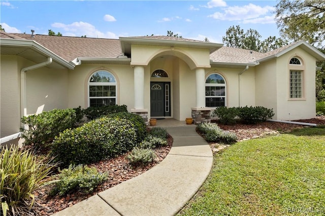 5799 N Oakmont Dr, Beverly Hills, FL 34465 - doorway to property with stucco siding, roof with shingles, and a yard