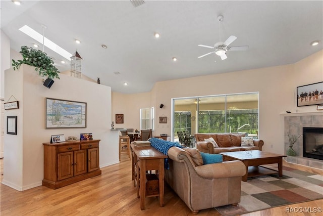 5799 N Oakmont Dr, Beverly Hills, FL 34465 - living room featuring light wood-style floors, a ceiling fan, a tiled fireplace, a skylight, and high vaulted ceiling