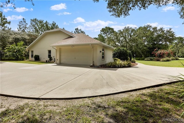 5799 N Oakmont Dr, Beverly Hills, FL 34465 - view of side of property featuring stucco siding, an attached garage, concrete driveway, a yard, and view of scattered trees