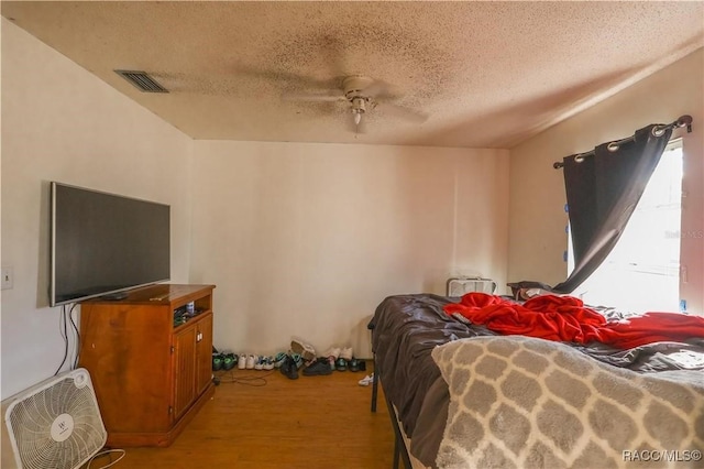 bedroom featuring ceiling fan, light wood-type flooring, and a textured ceiling