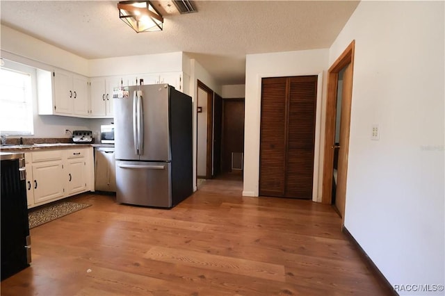 kitchen featuring a textured ceiling, dark hardwood / wood-style flooring, stainless steel appliances, and white cabinetry