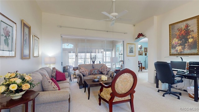 interior space featuring arched walkways, light carpet, and ceiling fan