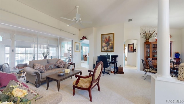 living room featuring light carpet, decorative columns, visible vents, arched walkways, and ceiling fan