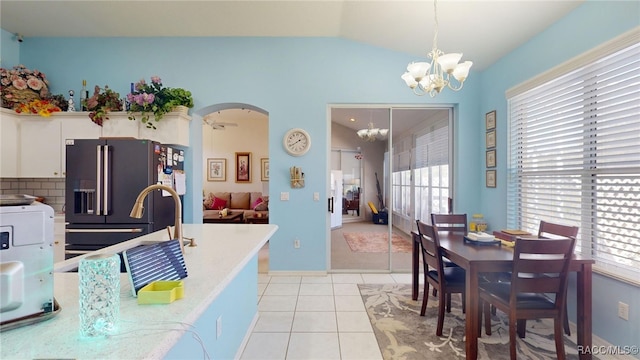 kitchen with arched walkways, light countertops, hanging light fixtures, white cabinets, and high end black refrigerator