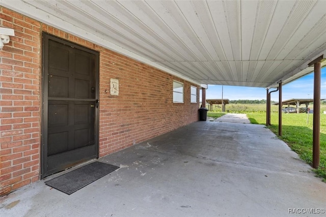 doorway to property with a carport and a lawn