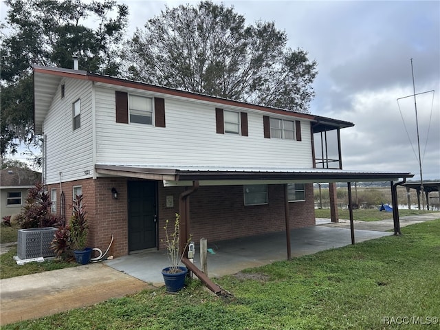 view of front of home featuring a front yard, a carport, and central AC unit