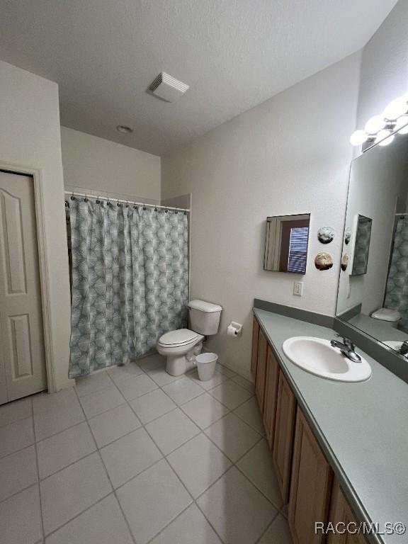 bathroom with toilet, a shower with shower curtain, vanity, tile patterned floors, and a textured ceiling