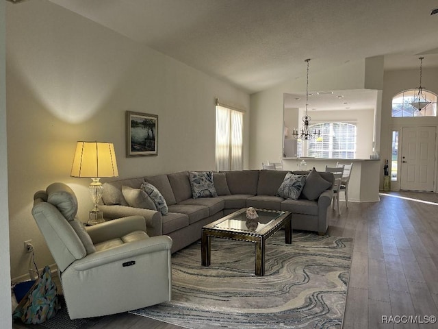 living room featuring lofted ceiling, hardwood / wood-style flooring, and an inviting chandelier