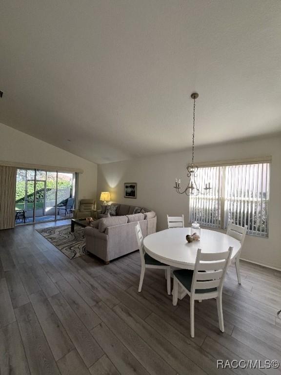 dining area featuring lofted ceiling, wood-type flooring, and a chandelier