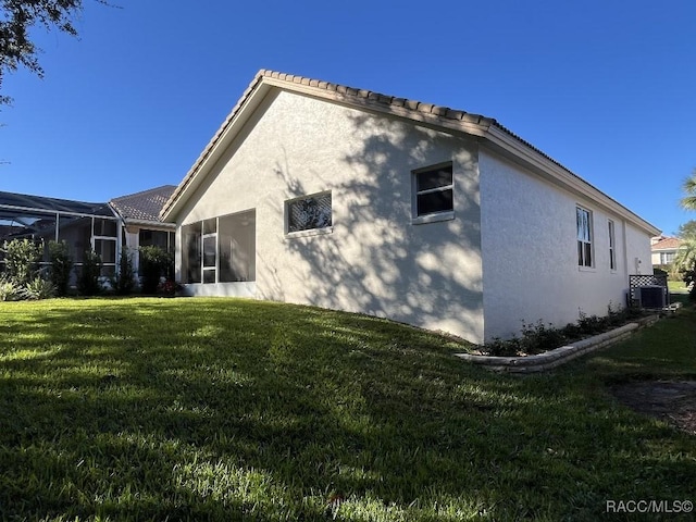 back of house featuring a lanai, central air condition unit, and a yard