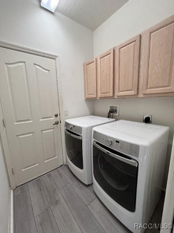 washroom with a textured ceiling, cabinets, and washer and dryer