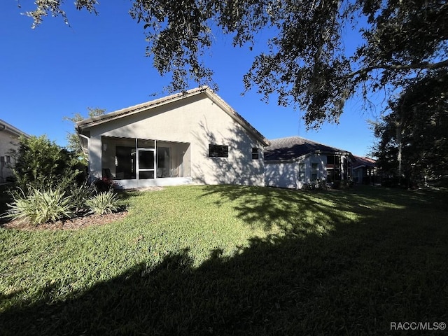 rear view of house featuring a yard and a sunroom