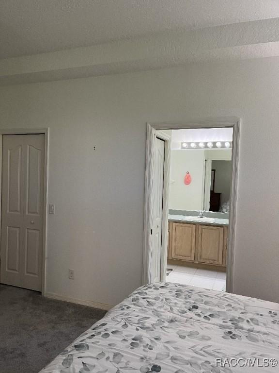 unfurnished bedroom with a textured ceiling, ensuite bathroom, and carpet