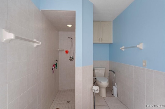 bathroom featuring tile patterned floors, tiled shower, toilet, and tile walls