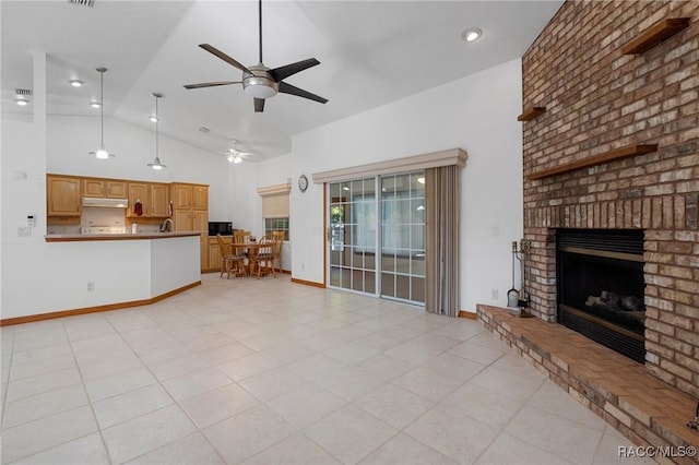 unfurnished living room with ceiling fan, vaulted ceiling, light tile patterned floors, and a brick fireplace