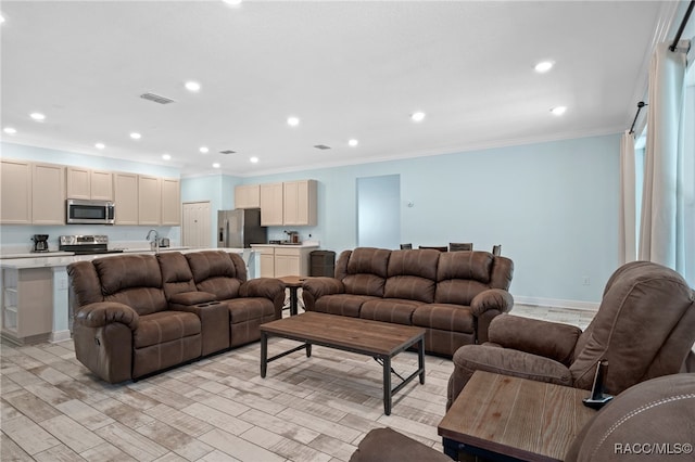 living room featuring crown molding, sink, and light hardwood / wood-style flooring