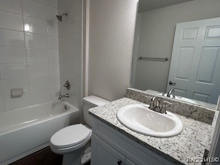 full bathroom featuring vanity, tiled shower / bath combo, and toilet