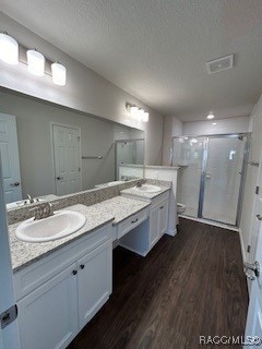 bathroom featuring hardwood / wood-style floors, vanity, an enclosed shower, and a textured ceiling