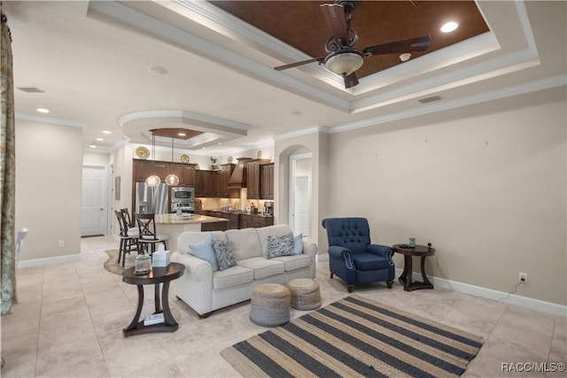 living room featuring ceiling fan, a raised ceiling, ornamental molding, and light tile patterned floors