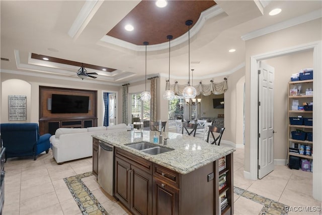 kitchen with ceiling fan with notable chandelier, a tray ceiling, ornamental molding, and an island with sink