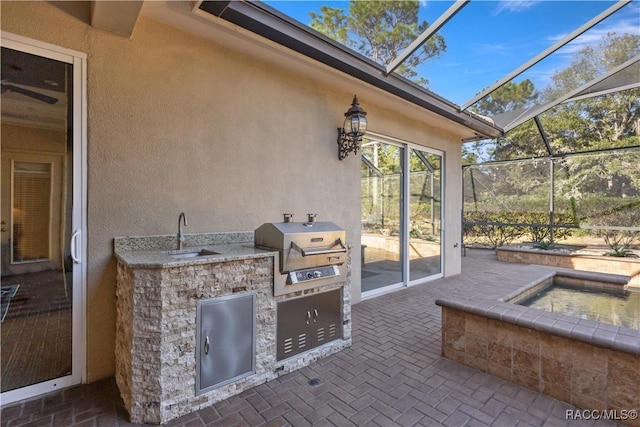 view of patio with a lanai, a grill, sink, and an outdoor kitchen