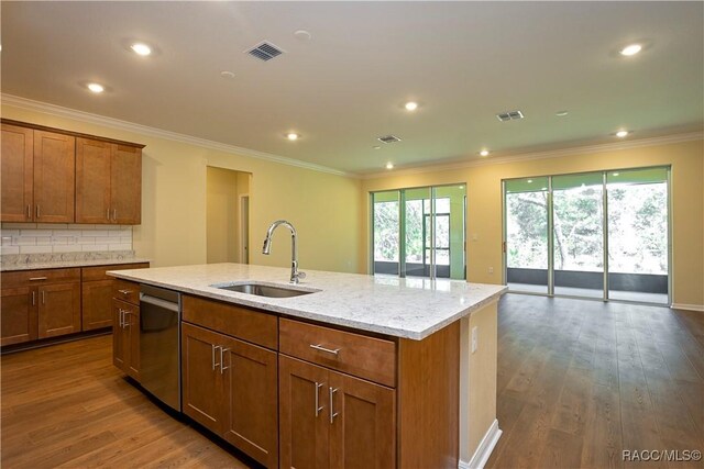 kitchen with ornamental molding, appliances with stainless steel finishes, hardwood / wood-style floors, and a center island with sink