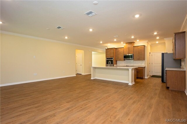 kitchen with light wood-type flooring, stainless steel fridge, light stone counters, and decorative backsplash