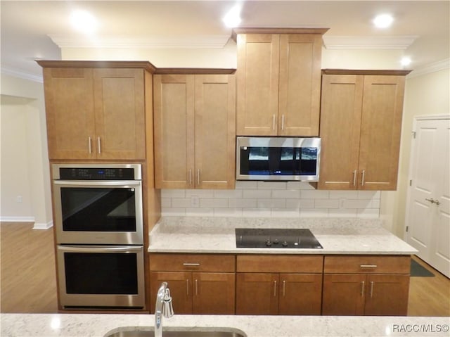 kitchen featuring sink, crown molding, appliances with stainless steel finishes, light stone countertops, and decorative backsplash