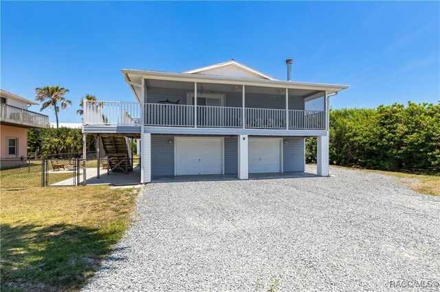 9 Flagler Dr, Palm Coast, FL 32137 - raised beach house featuring stairway, gravel driveway, fence, and an attached garage