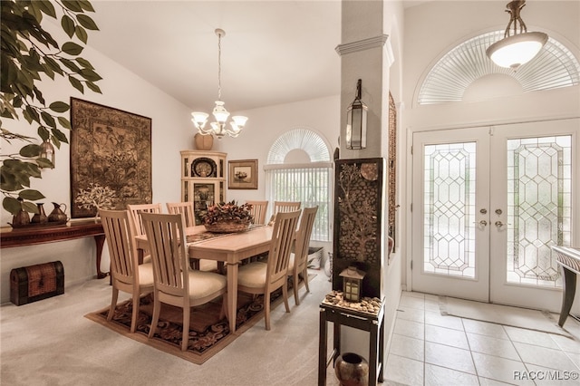 dining room featuring a chandelier, vaulted ceiling, light carpet, and french doors